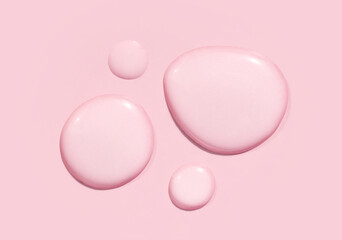 round drops of transparent gel serum on pink background