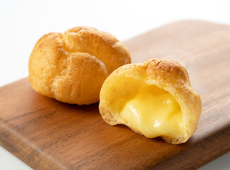 Cream puffs on a cutting board placed on a white background.