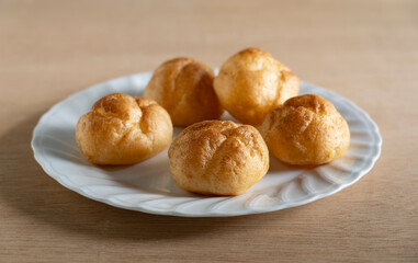 Cream puffs placed on a plate at the table.