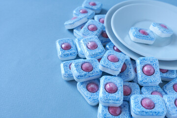 Detergent for dishwashers. Dishwasher detergent with clean dishes on blue background.