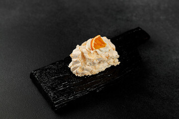 Meringue roll. Whipped proteins and sugar, filling - cream cheese based on soft cheese and cream on a black cutting board