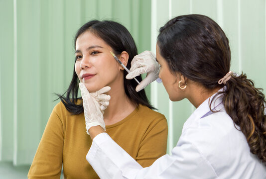 Doctor giving female patient medical injection in temporal. Atmosphere at cosmetic surgery department in hospital clinic.