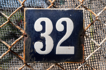 Weathered grunge square metal enameled plate of number of street address with number 32
