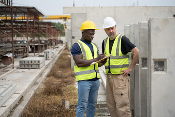 Portrait African engineer man working with caucasian engineer man at precast cement outdoor factory	