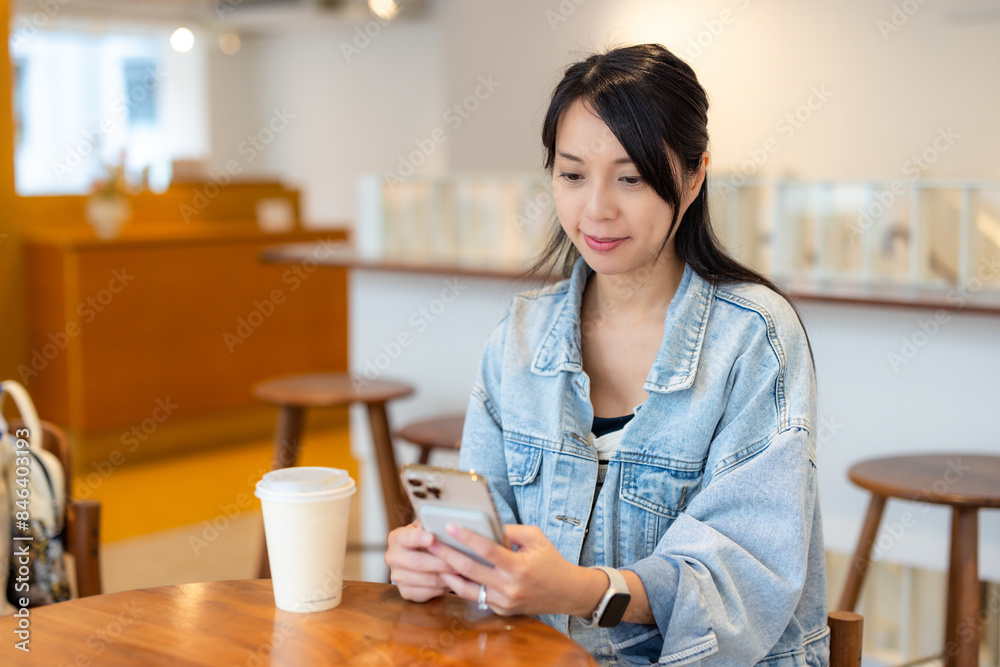 Wall mural Woman sit inside the coffee shop with her phone