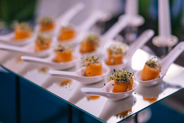 Delicious appetizers with engraved salmon greenery decorations on a small spoon.