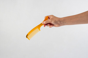 Brown hair comb in hand isolated on white background