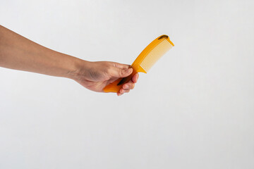 Brown hair comb in hand isolated on white background