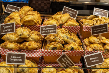 An empanada is a type of pastry baked or fried in Hispanic cultures. Mix set empanadas on outdoors bazar. Closeup of baked snack empanada at market, popular Spanish street food