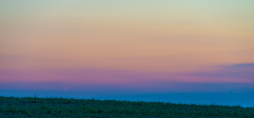 Sunset over fields and trees in a green hilly landscape under a colorful sky in sunlight in summer, Voeren, Limburg, Belgium, June, 2024