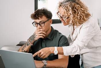 Young smiling boy studies at home with the support of a personal tutor using laptop. Blonde teacher...