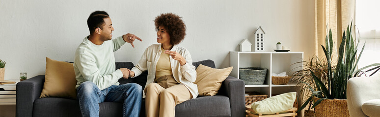 An African American couple sits on a couch, using sign language to communicate, showcasing the beauty of nonverbal communication.