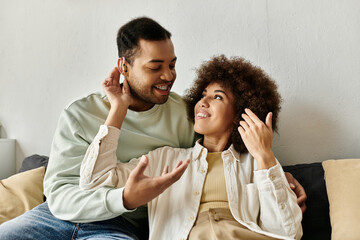 An African American couple uses sign language to communicate while sitting together on a couch.