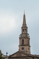 a tall church steeple has a clock and golden railing on it