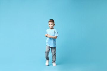 Happy little boy dancing on light blue background