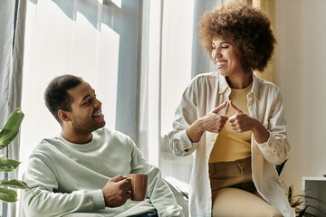 An African American couple uses sign language to communicate with each other while relaxing at home.