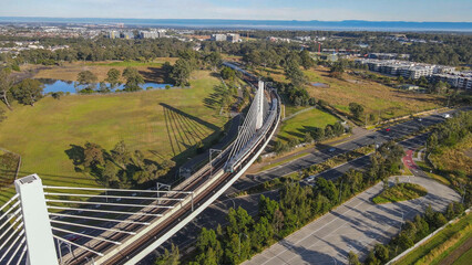Aerial drone view of a train crossing the railway bridge as it travels toward Rouse Hill Station on...