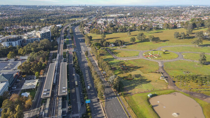 Aerial drone view above Rouse Hill Station on the metro northwest railway line, Greater Sydney, NSW Australia as a train departs the station toward Kellyville in June 2024 