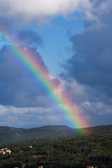 Rainbow over a small town and forest-covered mountains