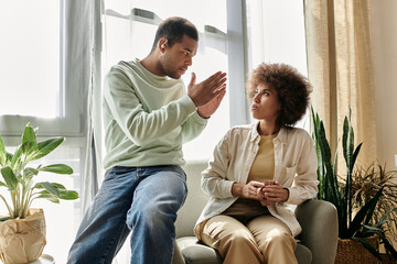 An African American couple sits at home and communicates through sign language.