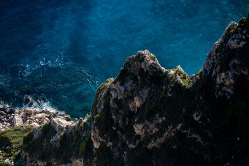 Rock formations and forest-covered mountain cliffs near blue ocean water