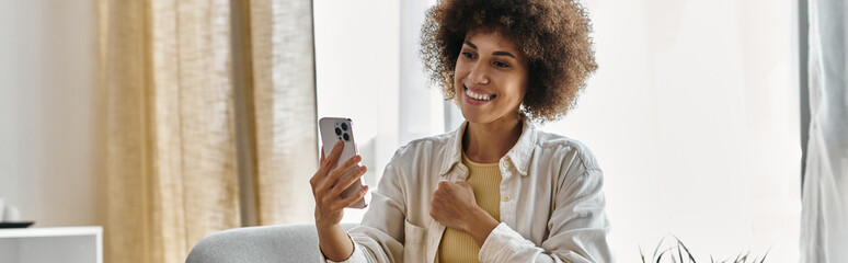 A woman smiles while using sign language on a phone in her home.