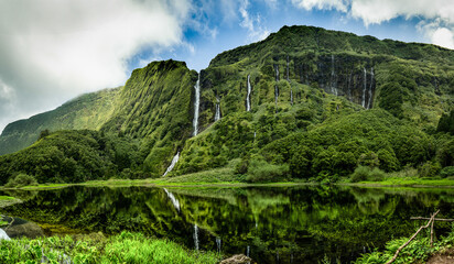 A stunning landscape of Flores Island in the Azores, a serene lake surrounded by lush mountains and...