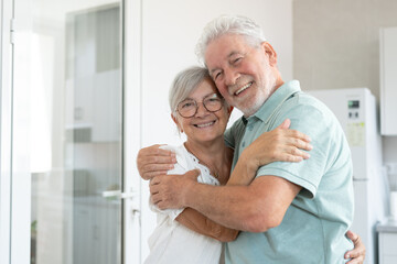 Fototapeta premium Handsome senior Caucasian couple hugging each other tenderly, exchanging cuddles and affection, concept of love, protection and care