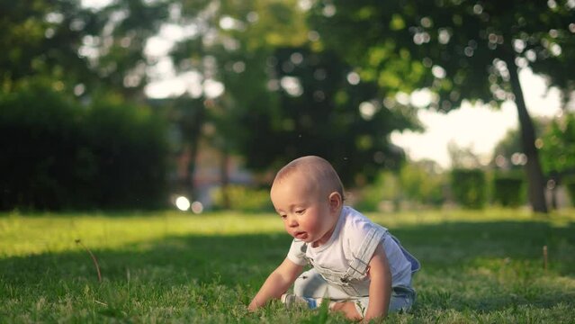 baby falls on the grass. happy family kid dream concept. baby learns to walk first steps failure fell on the grass in the summer in the park. failed attempt first steps lifestyle