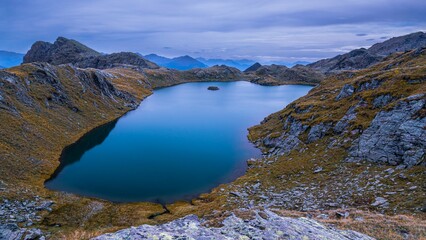 Naklejka premium Scenic landscape of lake surrounded by rocky mountains at twilight