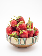 Red strawberries in a close-up view inside a bowl against a dark background