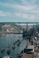 a group of boats docked next to a pier with several people walking on the sidewalk