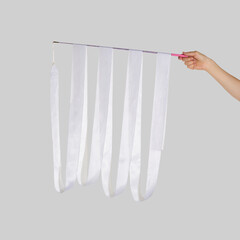 Hand of young gymnast holding white ribbon 