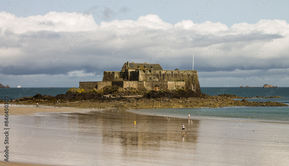 Wall mural people are walking along the beach in front of a castle