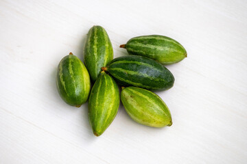 Fresh pointed gourd isolated on light wooden surface. It is also known as potol, parwal, palwal, or parmalin in different parts of Bangladesh and India.