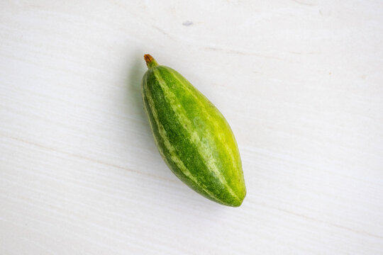 Fresh green vegetable pointed gourd (Trichosanthes dioica) isolated on light wooden background. It is also known as parwal, palwal, or parmalin in different parts of Bangladesh and India.
