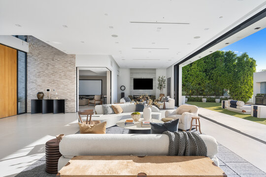 White spacious living room in a luxurious house connected to a large outdoor patio area