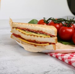 Half sandwich with cheese and tomato, beside fresh tomatoes