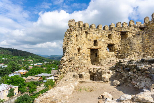 Ruined walls with loopholes and windows inside of Surami fortress. Village and mountains on background