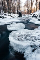 Sun setting over a partially frozen river with flowing water