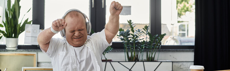 A man with inclusivity wearing headphones dances in an office setting.