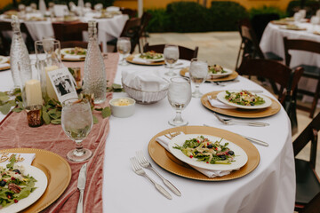 plates and cups on a table near two tables with white linens