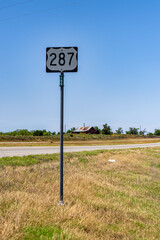 a street sign by a road that has a large number plate on it