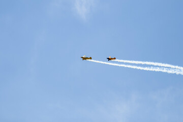 two airplanes flying in formation with smoke trailing across the sky
