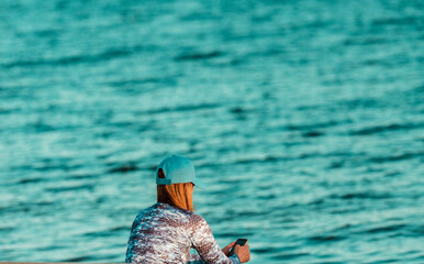 Woman wearing a blue hat by the sea