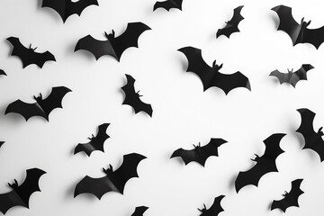 Fototapeta premium Black bats flying across a white background, ideal for spooky Halloween-themed projects and festive decorations.