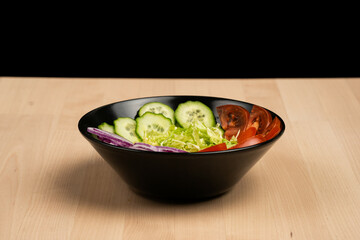 Various fresh vegetables in a bowl on rustic wooden table