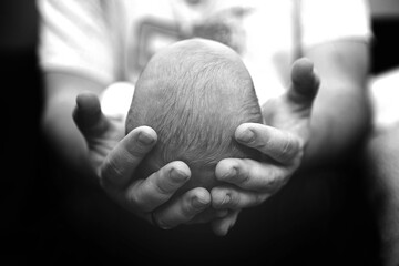 Man gently holds a baby's head with both hands