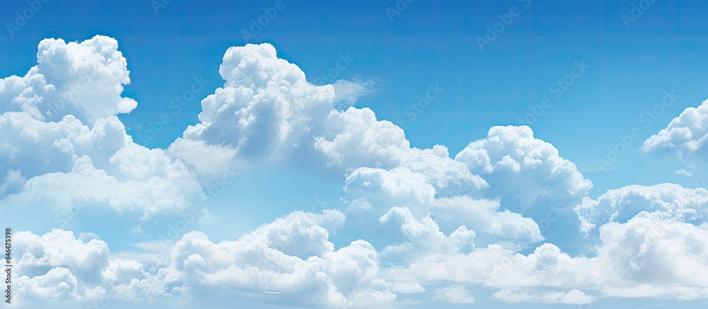 Poster Fluffy white clouds floating in a clear blue sky providing ample empty space for an image