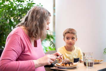 Grandmother and grandson having a waffle together in a cafe